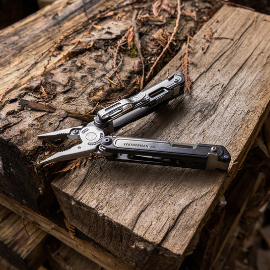 Translation missing: nl.An open Leatherman Arc, showcasing it's pliers and pocket clip, lies atop a piece of wood, emphasizing it's utility and craftsmanship