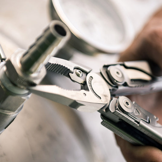 Translation missing: en.A person using the pliers on a Leatherman Surge to tighten nut on bolt, demonstrating practical skills with tools in a hands-on setting