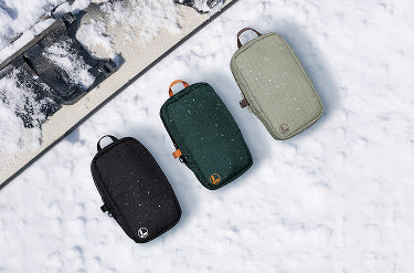 Translation missing: de.Black, hunter green, and mossy fog Leatherman tool pouches on a snowy background with a snowboard