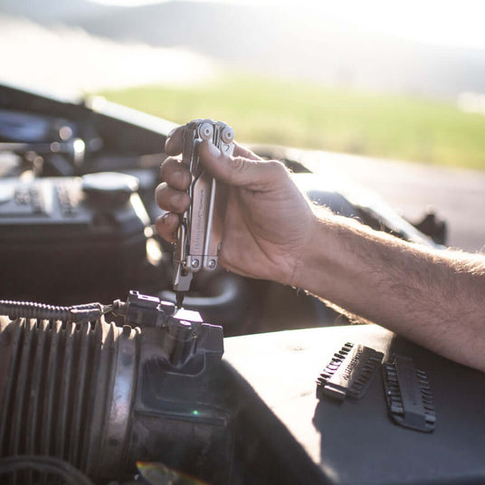 Translation missing: fr.Leatherman Surge being used to work on a truck with a bit kit set