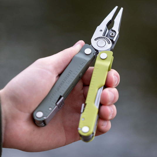 Translation missing: de.Mossy Slate Rebar held in a hand, open to showcase it's pliers, against a blurred background