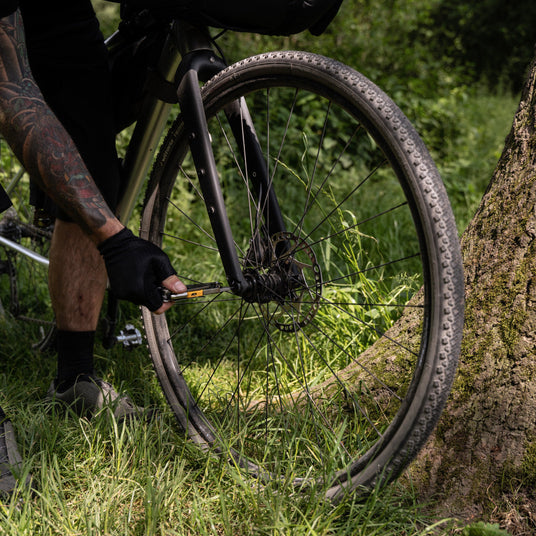Translation missing: fr.Person repairing a bicycle’s front wheel outdoors using Leatherman Signal