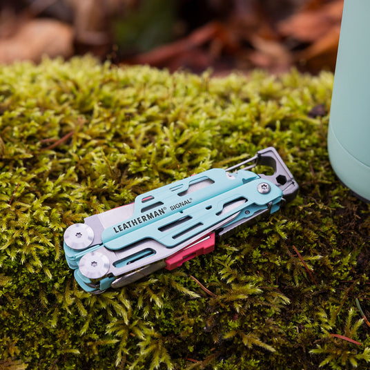 Leatherman Signal is placed on vibrant green moss, highlighting its sleek design amidst the earthy texture.