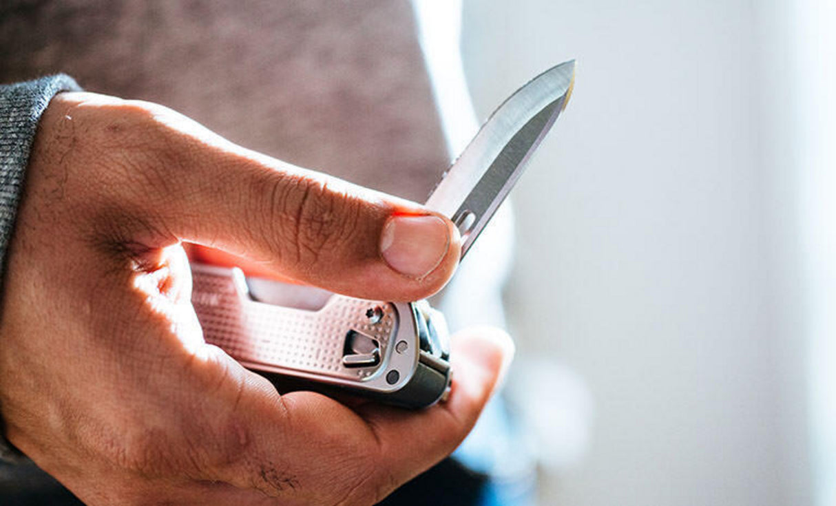 Translation missing: pl.Man in gray sweatshirt opening knife blade on Leatherman T4