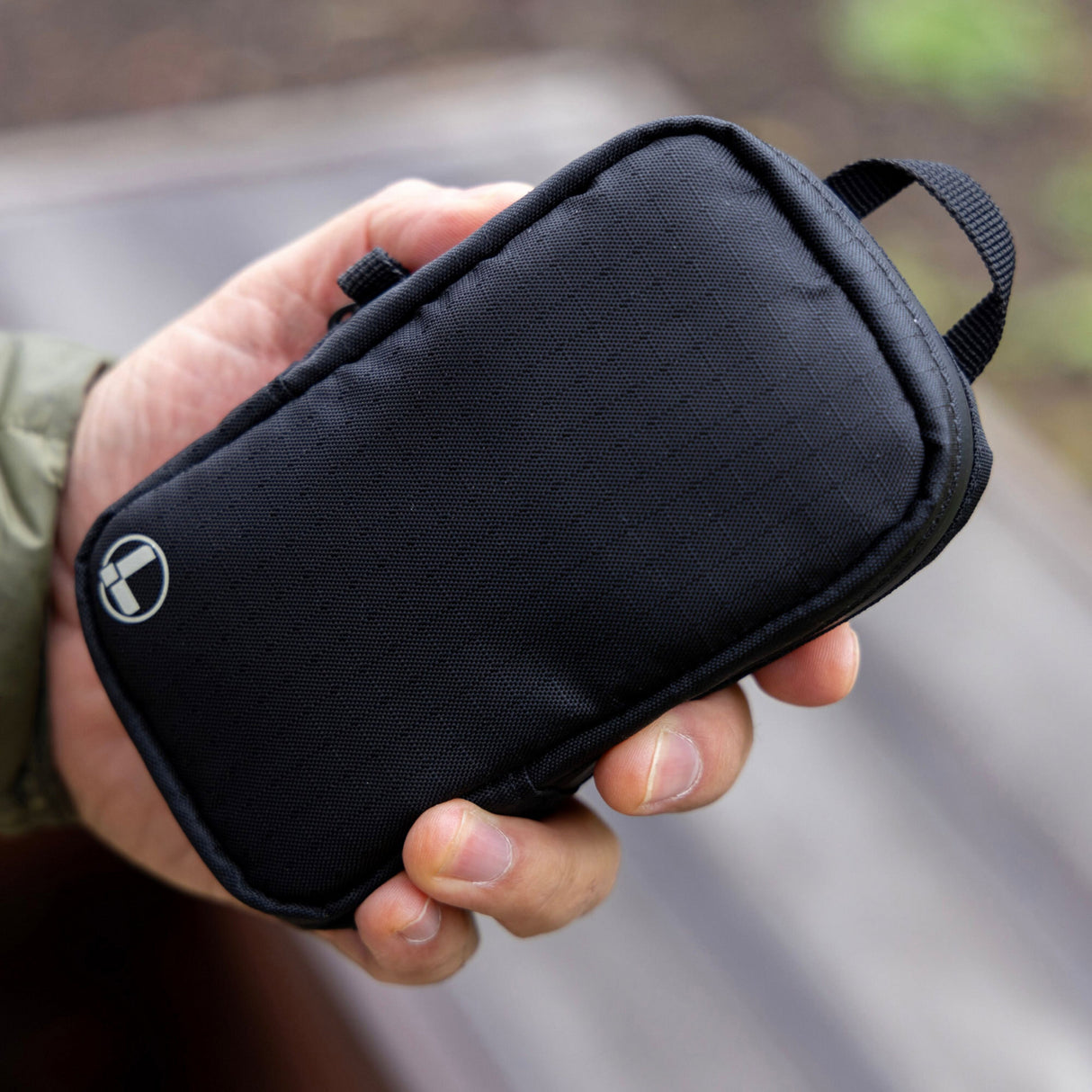 Translation missing: de.A person holds a compact black Leatherman Tool Pouch with a stitched logo and top loop, showcasing its durable construction and convenient size for everyday carry
