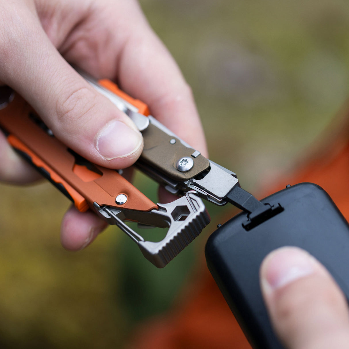 A person Leatherman Signal to open battery compartment, focused on a task or project.