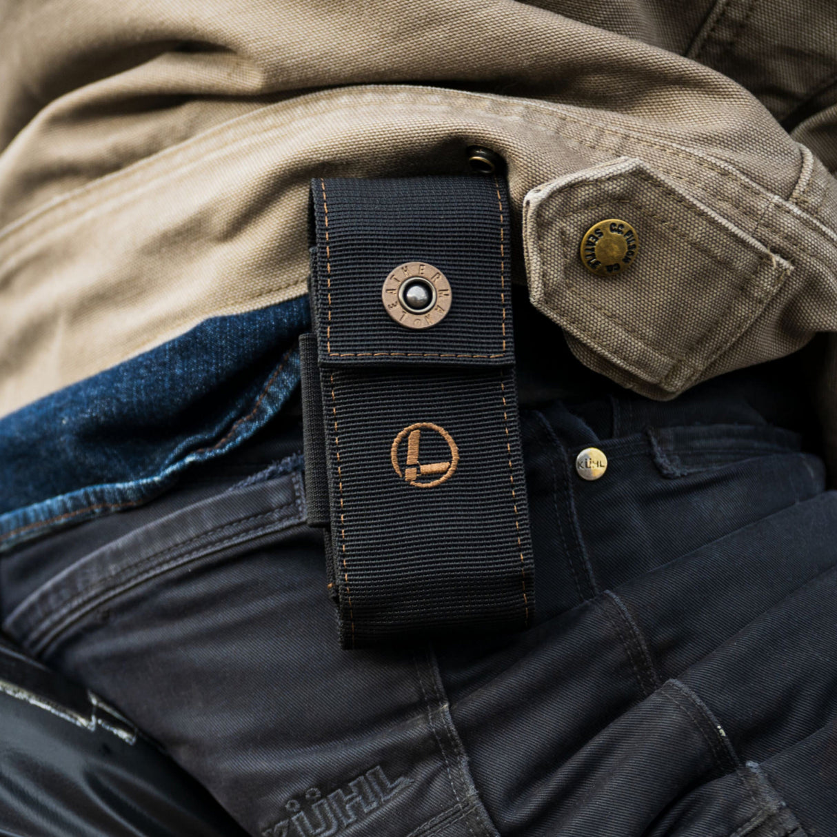 Translation missing: de.A man wearing a Leatherman Black Bronze Nylon Sheath positioned on his back, ready for carrying a Leatherman tool