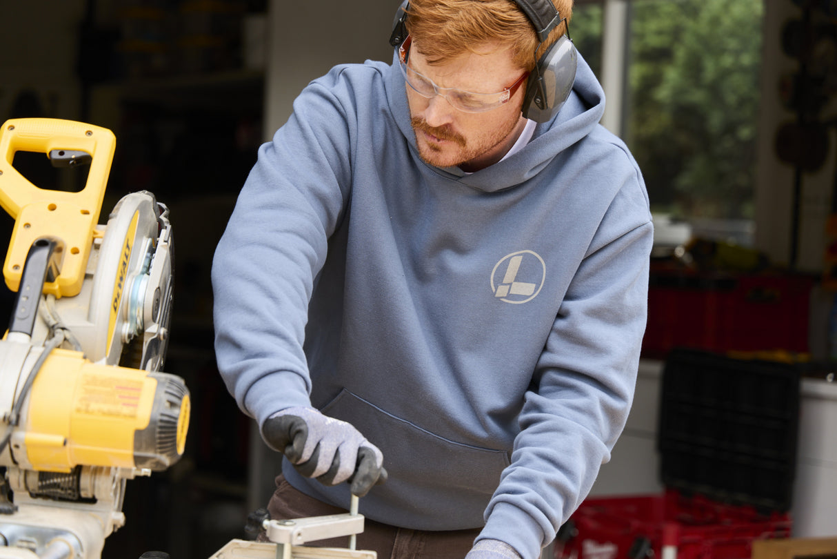 Translation missing: en.A person wearing a storm blue Leatherman Classic Hoodie operating a saw while working on a woodworking project