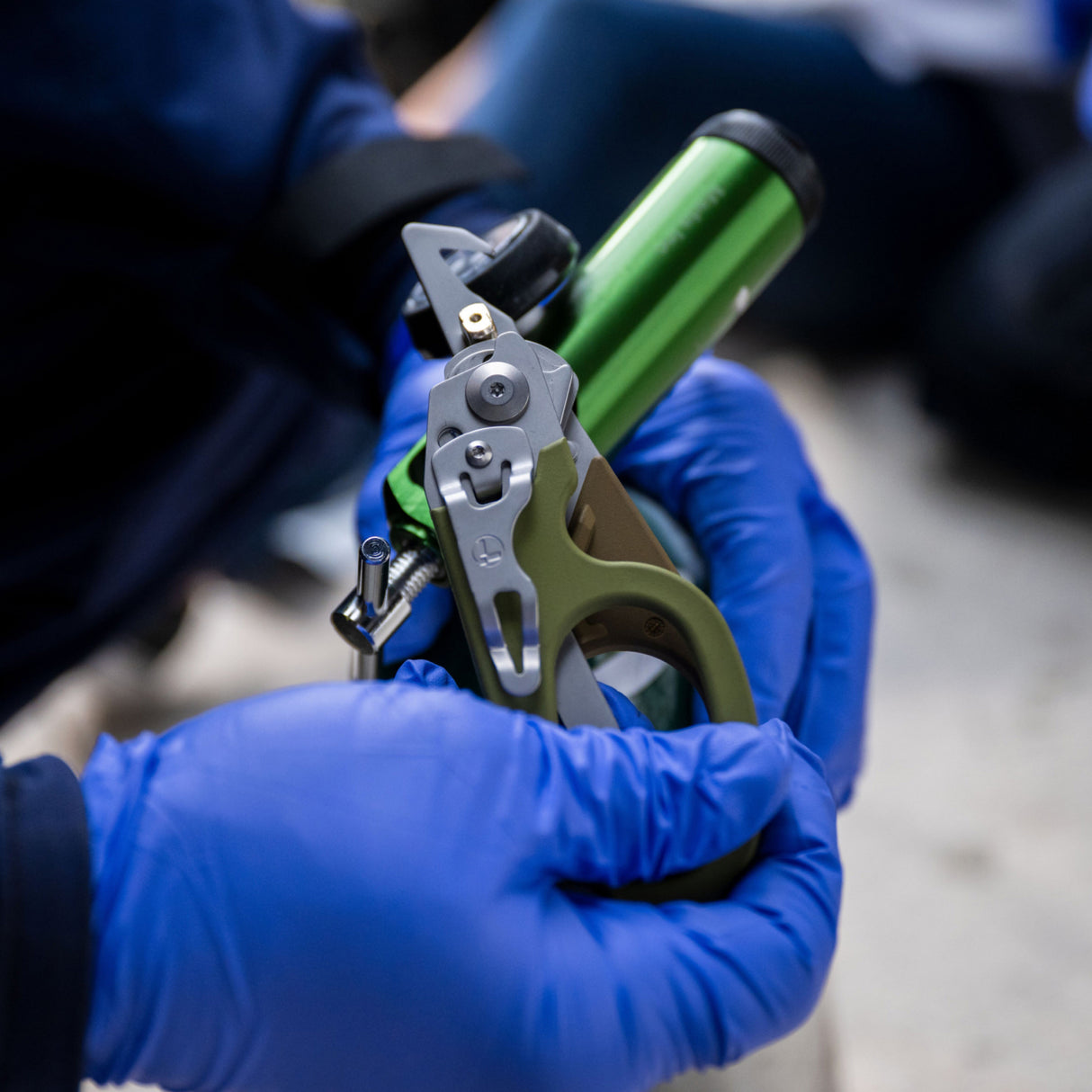 Translation missing: es.A nurse wearing blue gloves uses the oxygen tank wrench on a Leatherman Woodland Raptor Rescue to open an oxygen tank