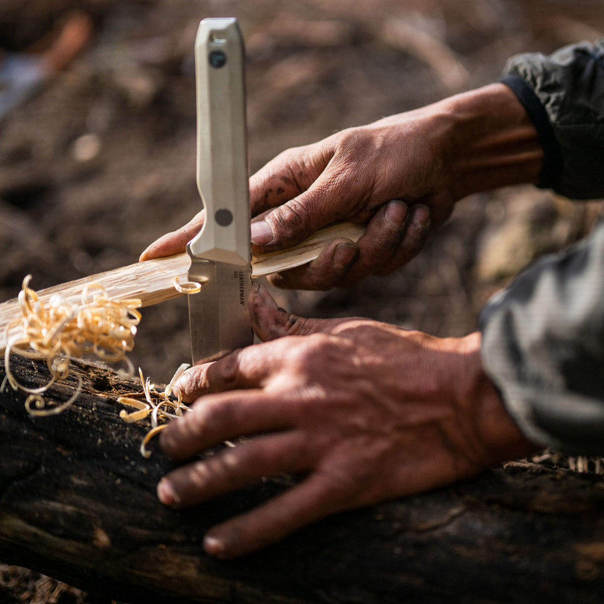 Translation missing: fr.An individual carefully cutting wood with a Leatherman Alpine Pioneer knife, demonstrating craftsmanship and attention to detail