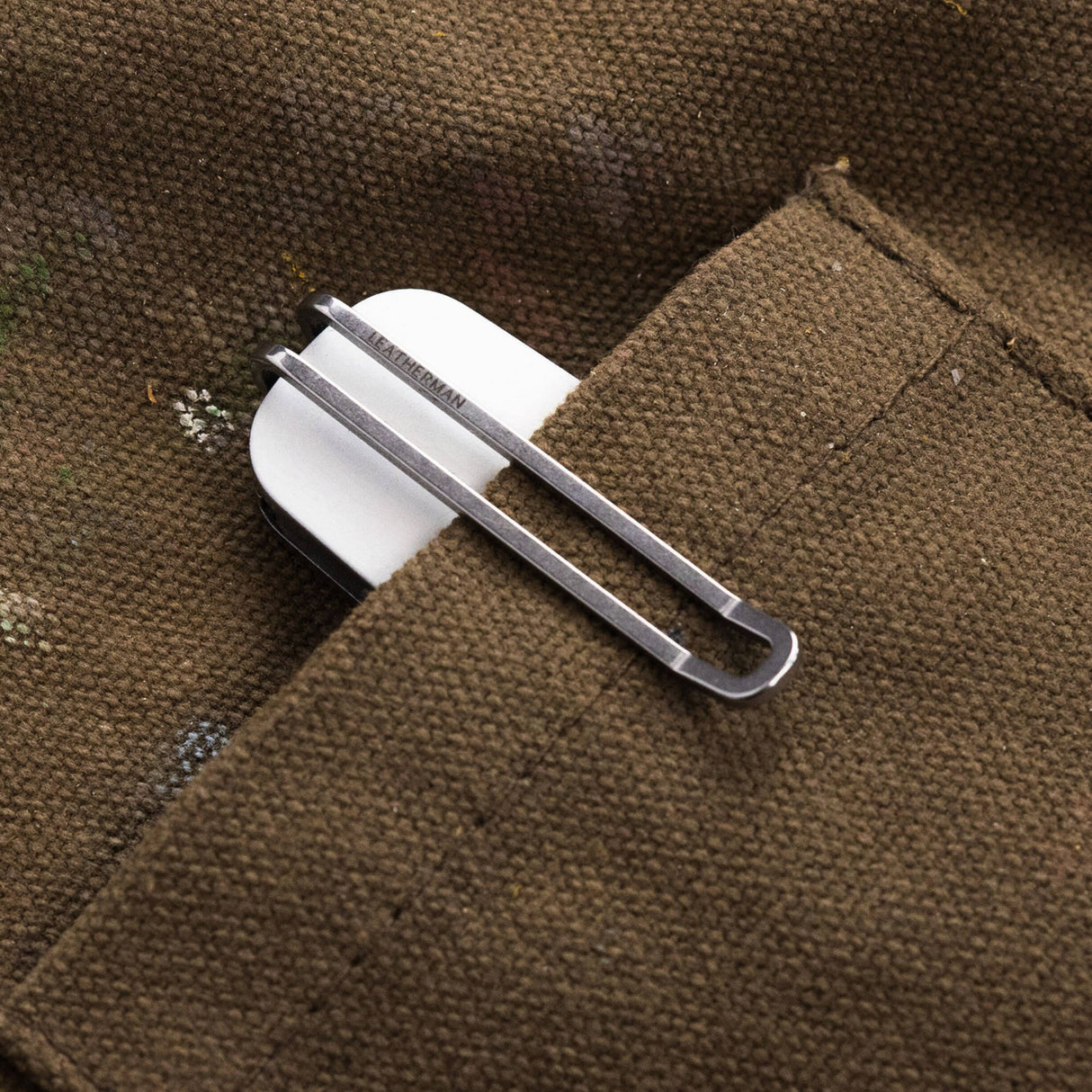 Translation missing: fr.Leatherman Blazer Alpine folding knife clipped inside the pocket of a brown utility garment, with only the white handle and deep-carry pocket clip visible, highlighting convenient everyday carry