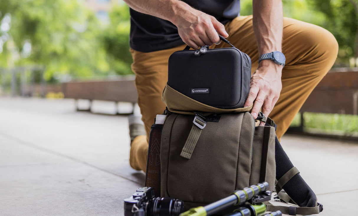 Translation missing: fr.Man placing Leatherman® Adapt Kit in crossbody bag