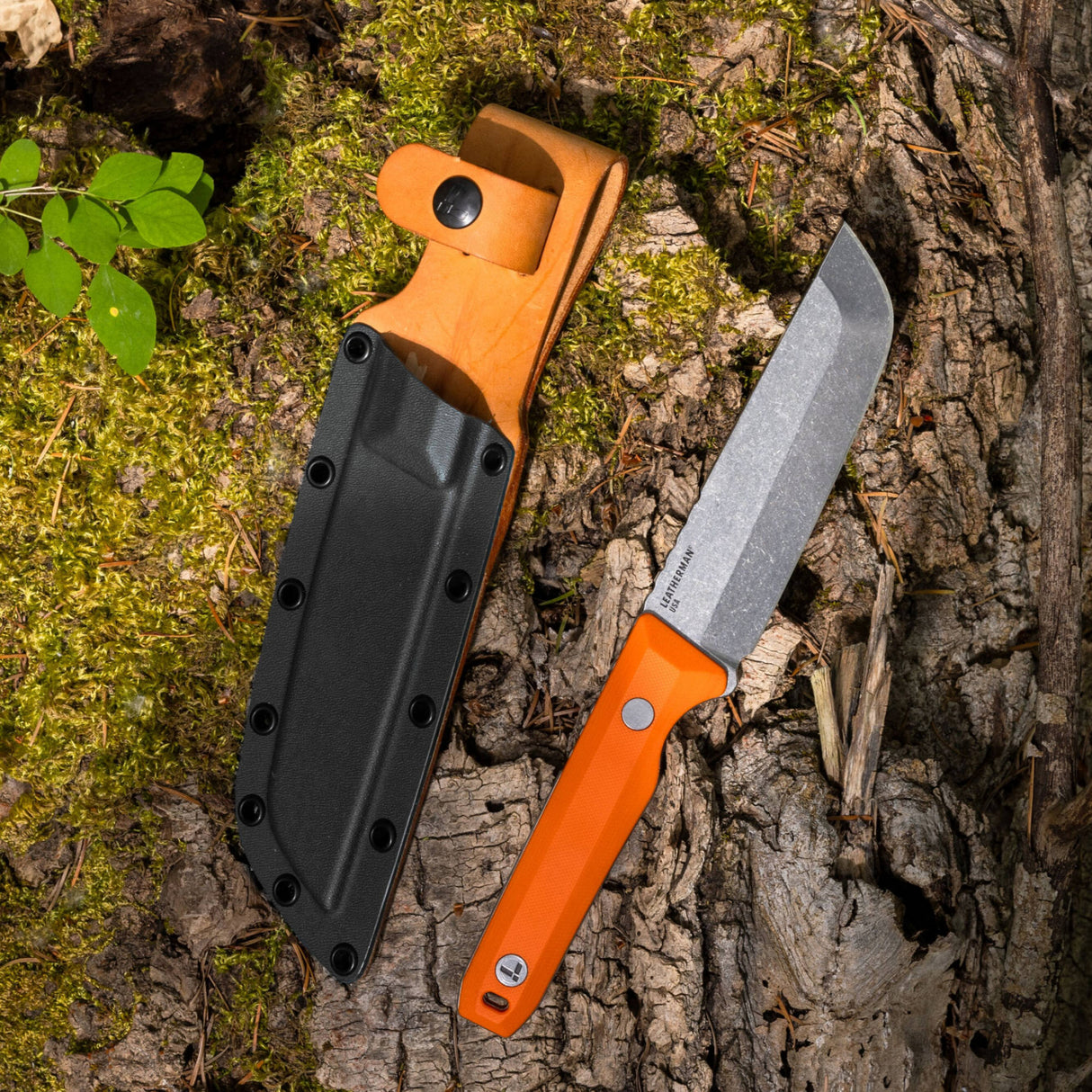 Translation missing: es.Leatherman Pioneer knife alongside a sheath lies on the ground, with natural elements like dirt and grass around them