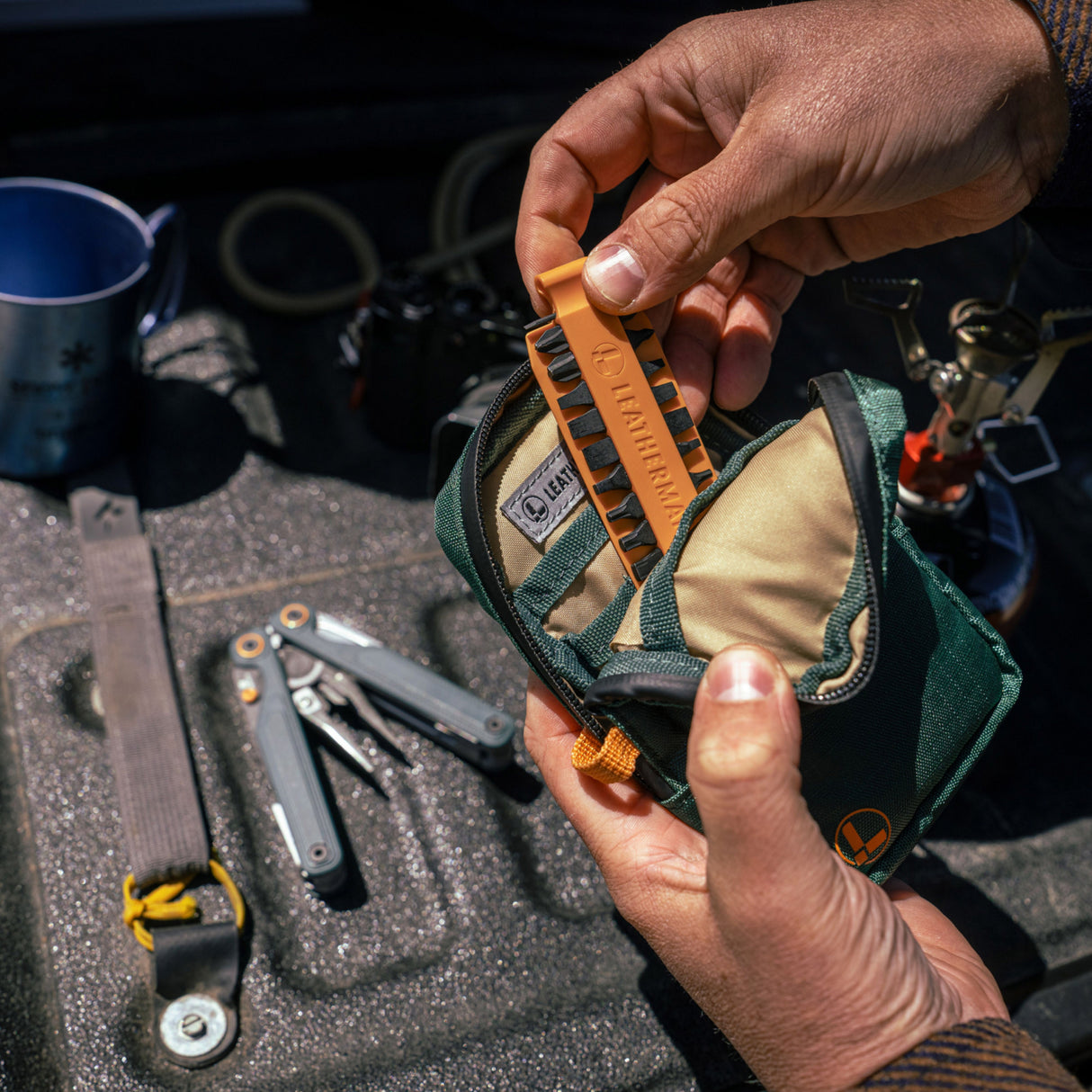 Translation missing: de. A person placing Orange Leatherman Bit Kit into Tool Pouch