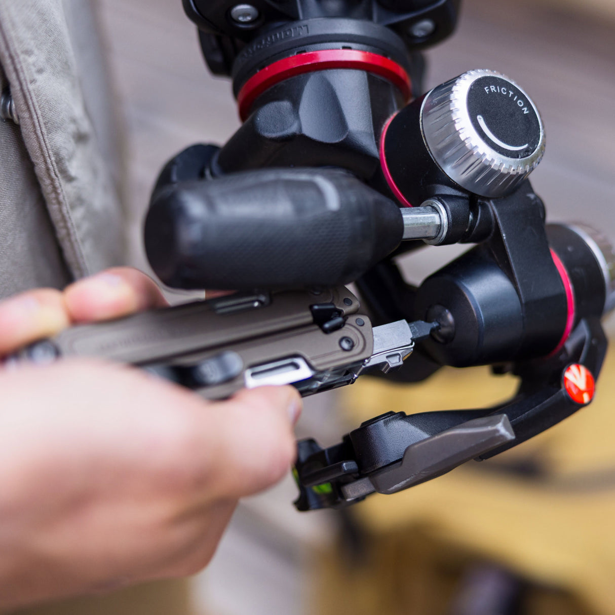 Translation missing: en.Person using a Leatherman ARC® Talos multitool to tighten a camera tripod for precision adjustments