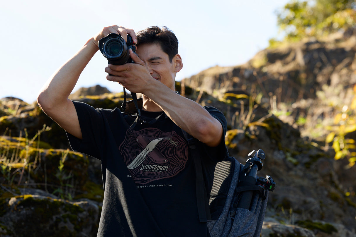 Translation missing: en.A photographer wearing a black Leatherman Blade & Grain Tee while taking a pictures outdoors