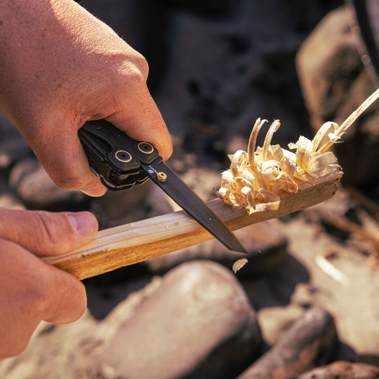 Translation missing: de.Person using the Obsidian Leatherman Wave® Alpha multitool to shave wood outdoors