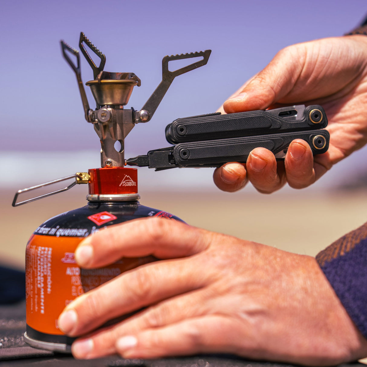 Translation missing: de.Close-up of a hand using an Obsidian Leatherman Wave® Alpha multitool to attach fuel to a camping stove