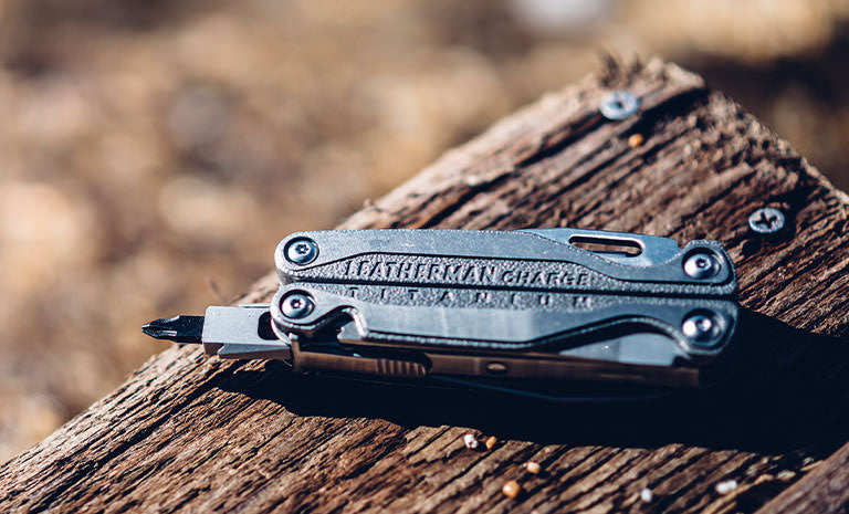 Translation missing: en.Leatherman Charge+ TTI laying on piece of wood under sunlight