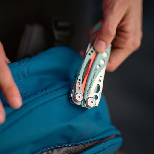 Translation missing: de.Person holding closed Skeletool CX over a backpack