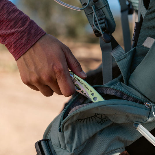 Translation missing: en.Person putting a closed Skeletool KB into a backpack