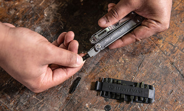 Translation missing: de.Man replacing a bit from Leatherman Bit Kit on Leatherman Curl over wood table