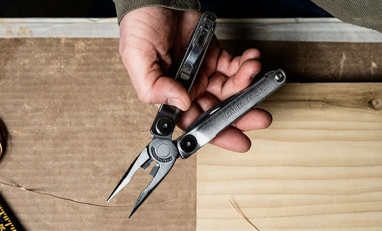 Translation missing: de.Man holding opened Leatherman Curl over table