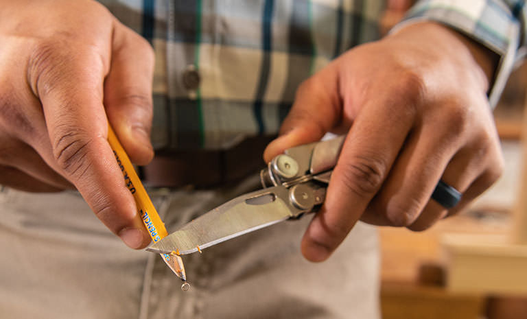 Translation missing: de.Man using knife blade on Leatherman Curl to sharpen yellow pencil