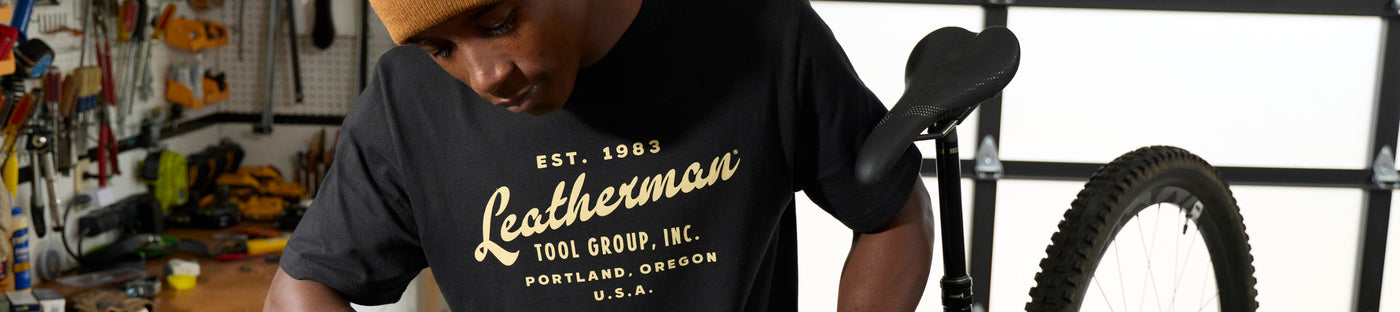 Translation missing: es.Man wearing a black Leatherman Vintage Tee in a workshop setting