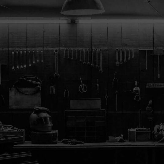 Translation missing: en.A dimly lit workshop with various tools hanging on the wall, a workbench, and storage drawers