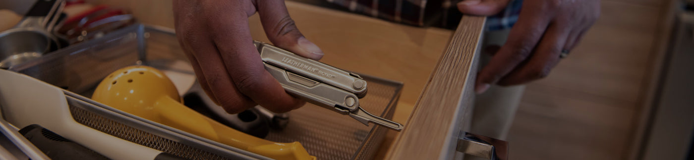Translation missing: en.A person is seen holding a Leatherman Bond in a drawer, surrounded by assorted utensils