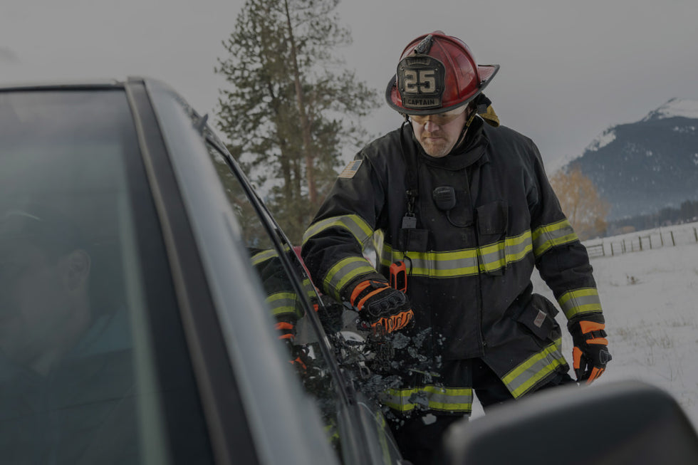 Translation missing: de.A firefighter stands beside a car, wearing protective gear and looking ready for action