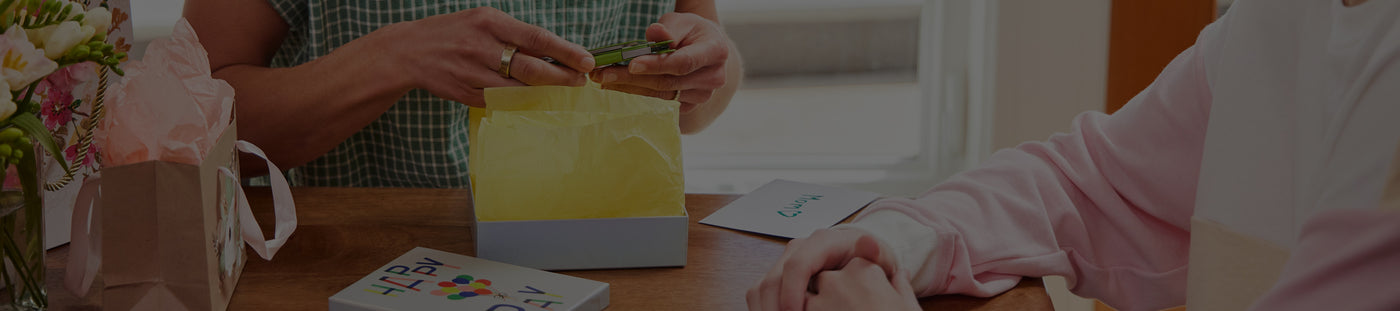 Translation missing: it.A mother opens Leatherman gift from son sitting at a table, capturing a moment of happiness and connection between them