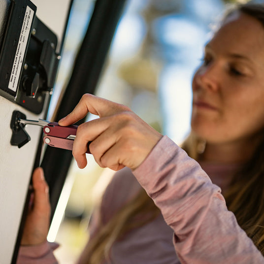 A woman using a Leatherman Bond to repair a door, showcasing her resourcefulness.