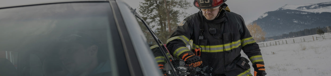 Translation missing: de.A firefighter stands beside a car, wearing protective gear and looking ready for action