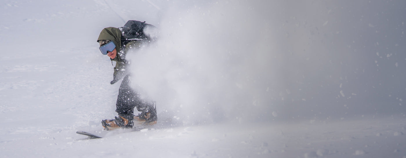 Translation missing: en.Person snowboarding in deep powder snow with a blue sky background