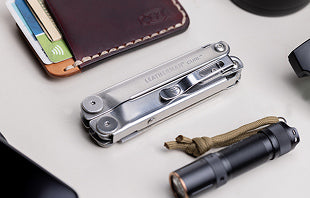 Translation missing: nl.A collection of items including a wallet, a cell phone, Leatherman Curl and a flashlight arranged on a flat surface