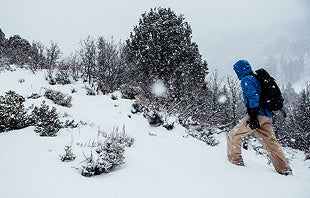 Translation missing: nl.A man with a backpack walks through a snowy landscape, leaving footprints in the fresh snow
