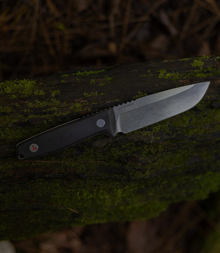 Translation missing: nl.Leatherman Trac in soft focus, placed on a mossy log, showing off the state of the art Magnacut steel blade and g10 handle