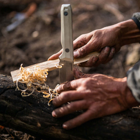 Translation missing: es.Alpine Leatherman Pioneer planted in a log and braced by rough hands to help make feather stick tinder