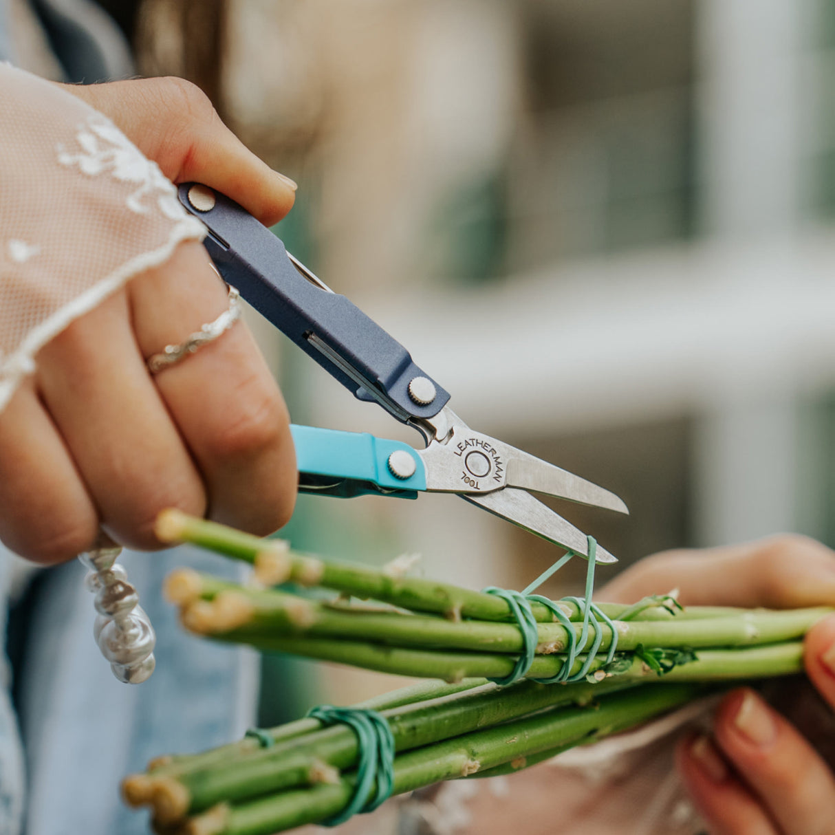 Translation missing: fr.Person using the scissors on a Leatherman Micra® in Lavender Mist color to cut the rubber band holding flower stems