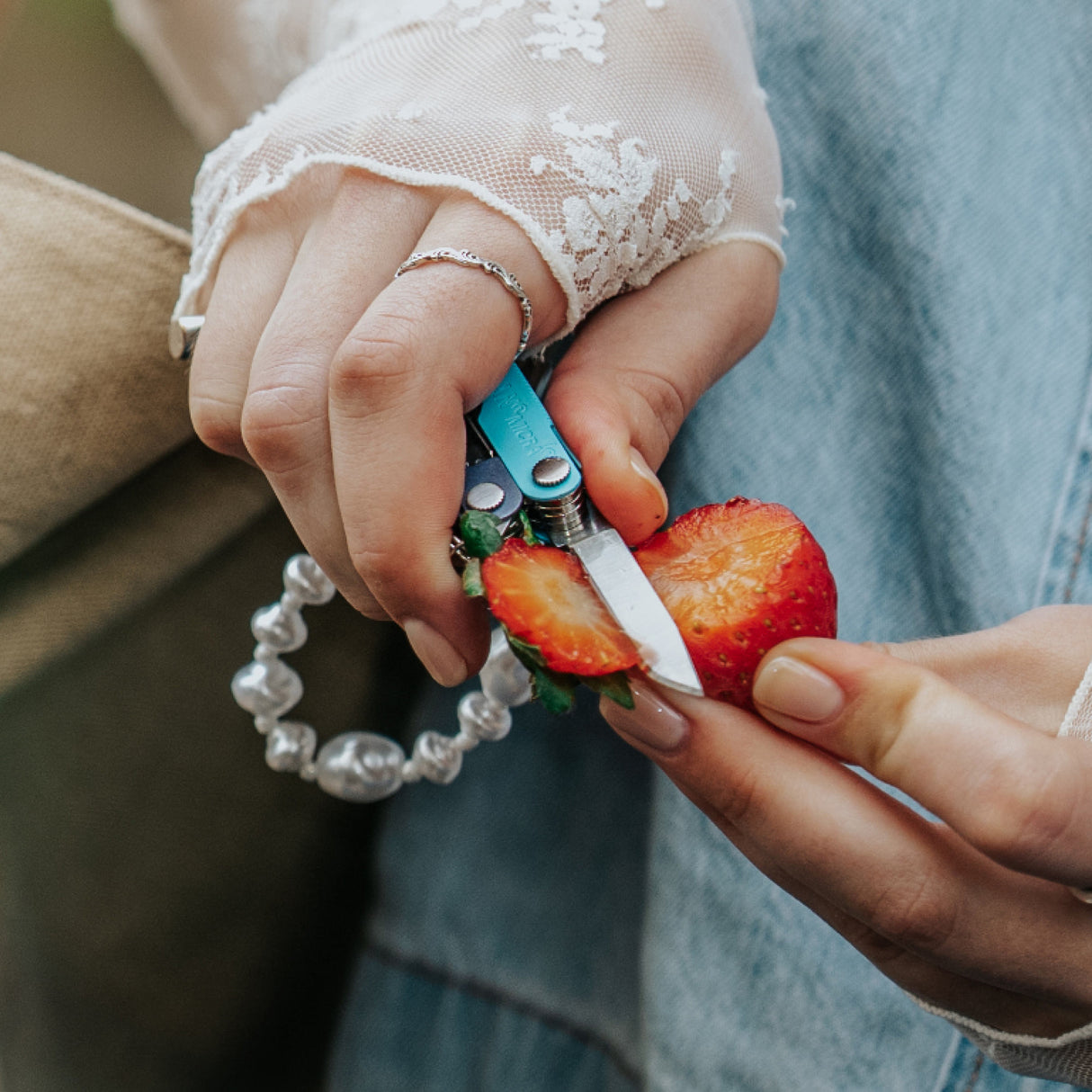 Translation missing: fr.Person using the knife on a Leatherman Micra® in Lavender Mist color to slice the top off of a strawberry