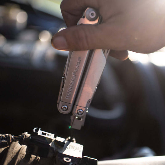 Translation missing: nl.Close-up of a hand using a Leatherman Surge to work on a small mechanical device
