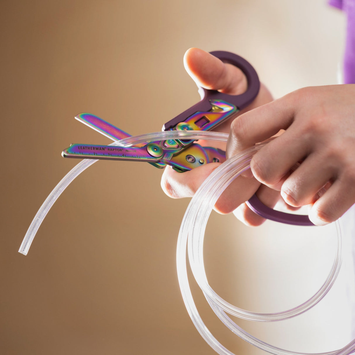 Translation missing: de.Hands using a Rainbow Raptor® Rescue tool to cut clear flexible tubing