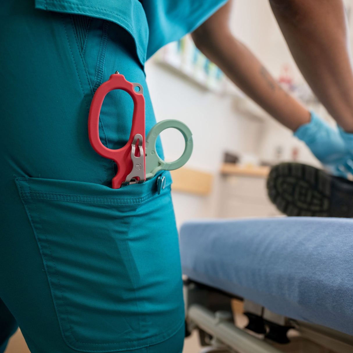 Translation missing: en.Person in teal scrubs with a South Beach Leatherman Raptor® Rescue open in the side pocket of the scrub pants