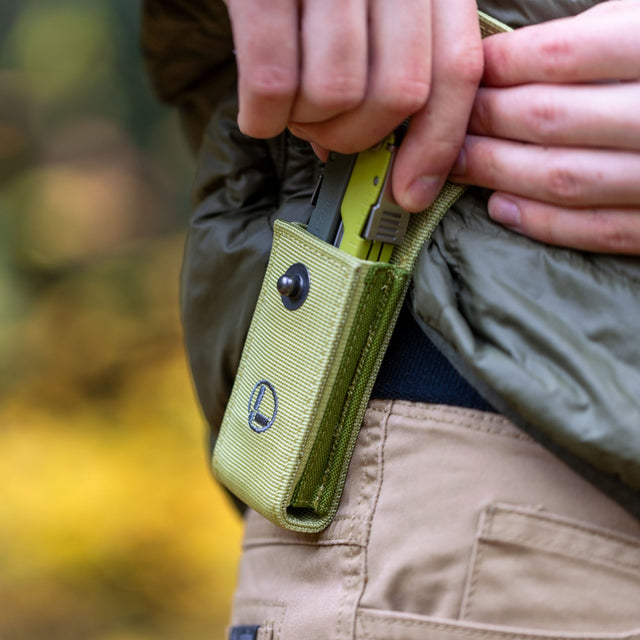 Translation missing: de.Person wearing a green jacket holstering a Mossy Slate Leatherman Rebar® in a matching sheath on their hip
