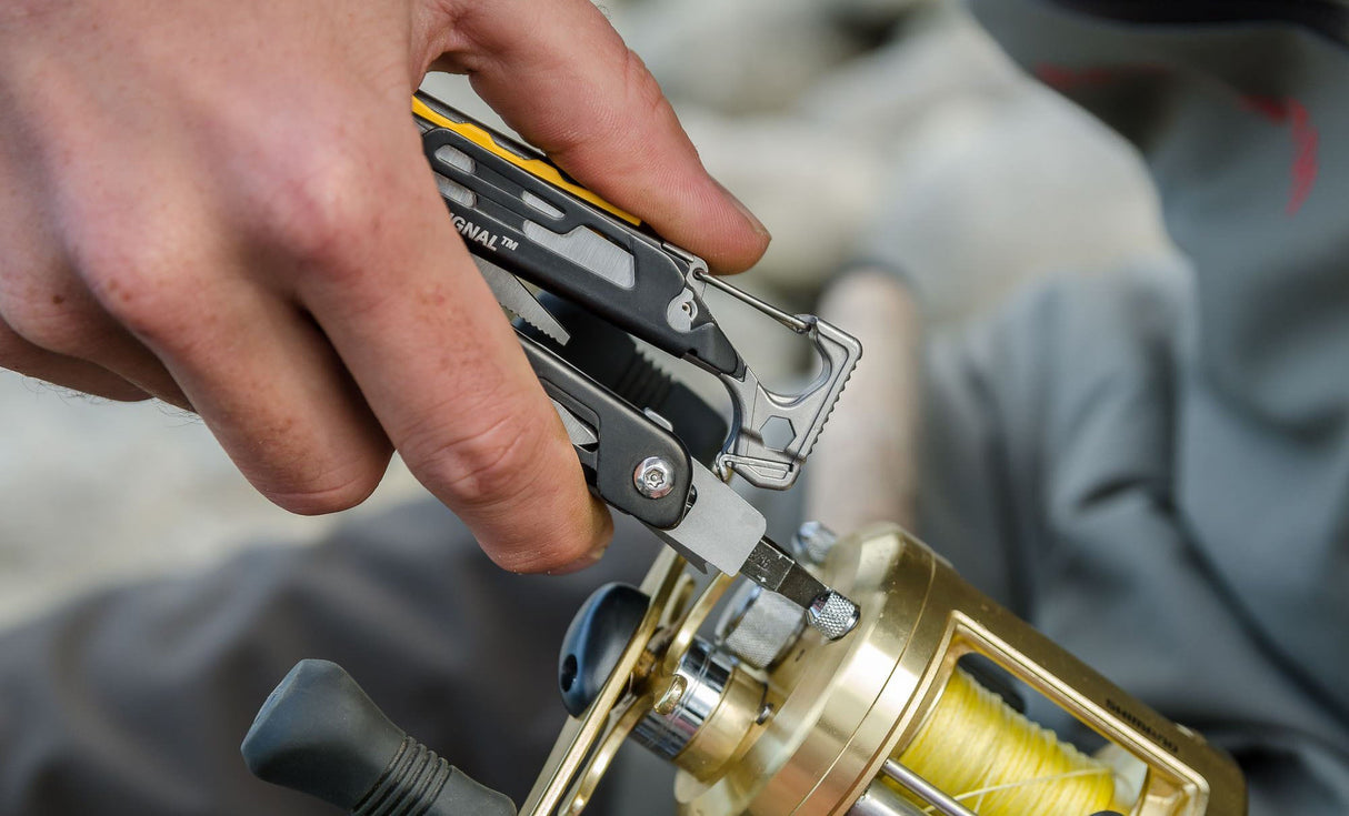 Translation missing: pl.Person using a black and stainless Leatherman Signal® multitool to tighten a fishing reel