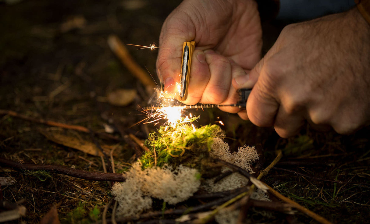 Translation missing: pl.A person using the ferro rod on a Leatherman Signal® to create sparks while preparing kindling in the forest