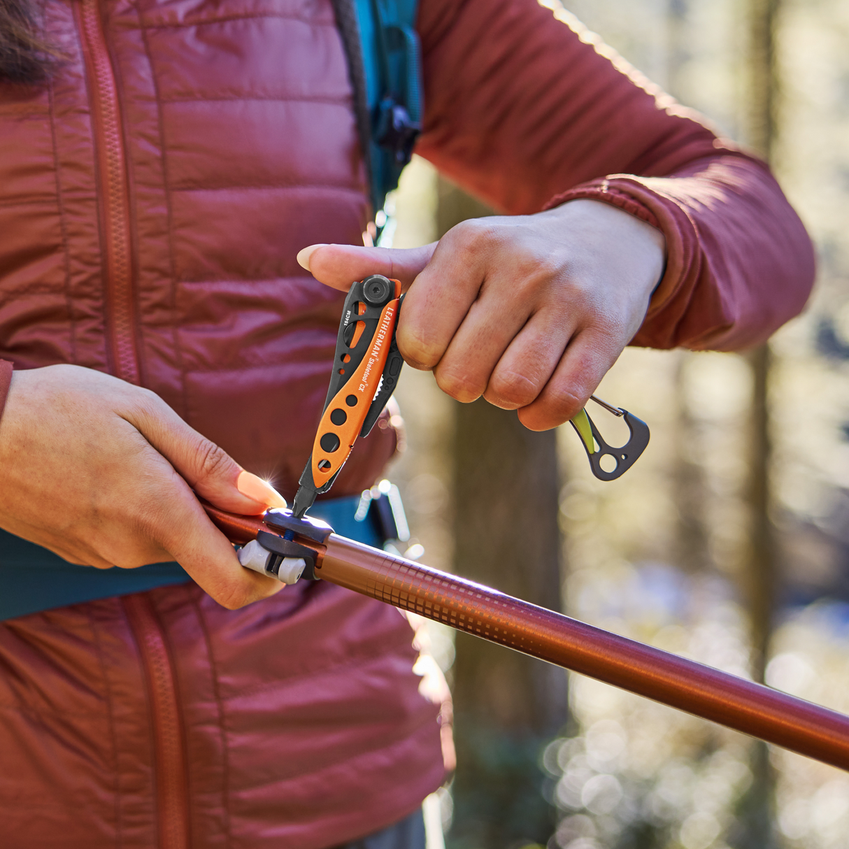 Translation missing: de.Person using a Leatherman Skeletool® CX in Aurora color to adjust a hiking pole outdoors