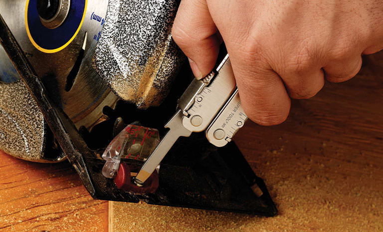 Translation missing: es.Man using Leatherman Super Tool 300 to tighten screw on saw machine